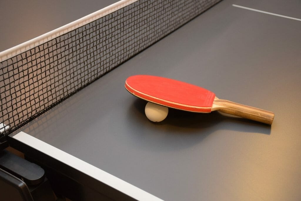 Two rackets on a ping pong table with standard ping pong table dimensions.
